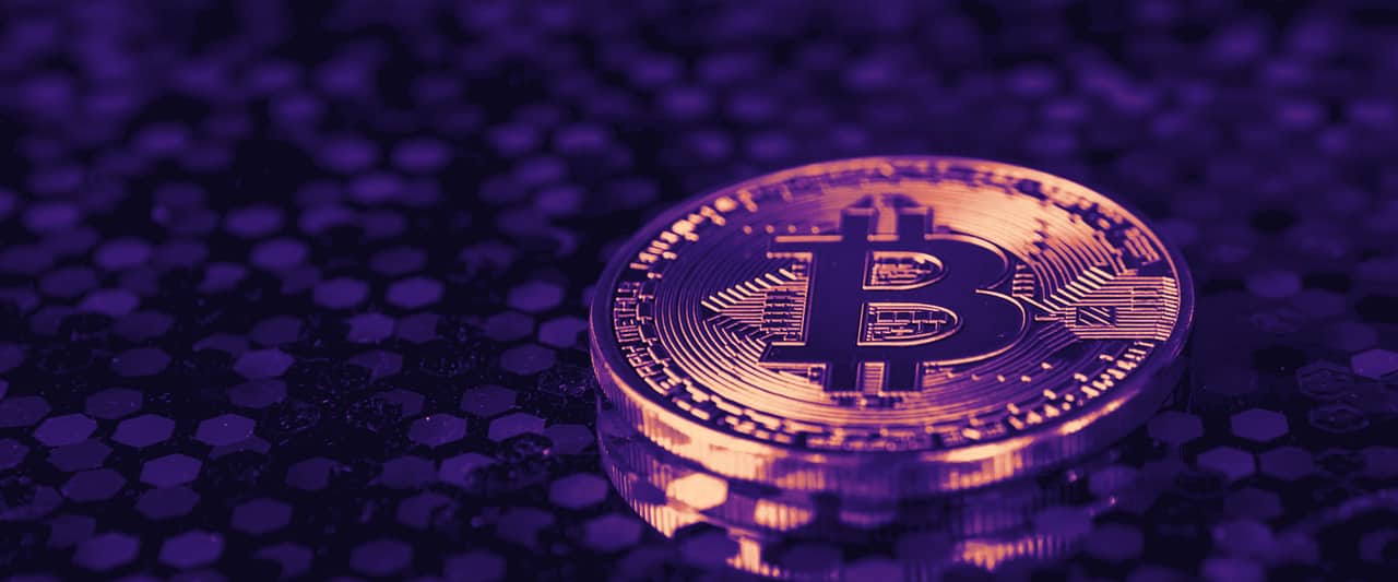 A physical bitcoin token on a textured surface