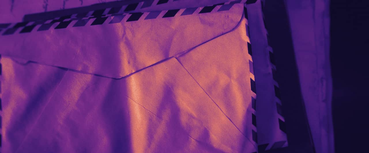 A stack of windowed paper envelopes on a grey surface