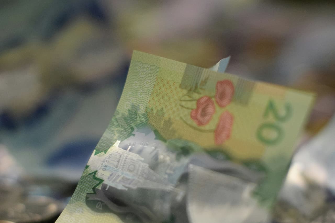 A crumpled Canadian twenty dollar bill among loose coins