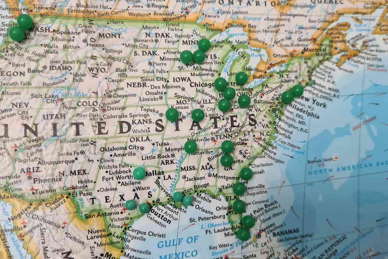 A paper map of the United States with green pins stuck in it