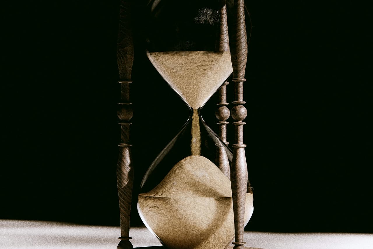 An antique wooden hourglass with sand running through it