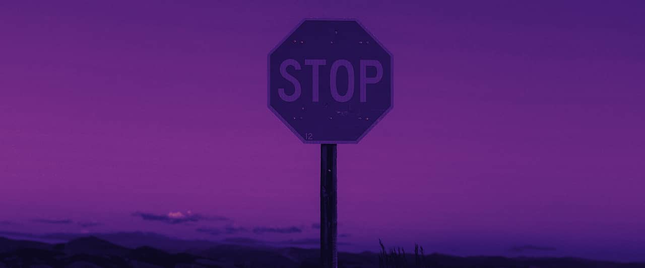 A red stop sign on a post in a grassy field under a pale sky