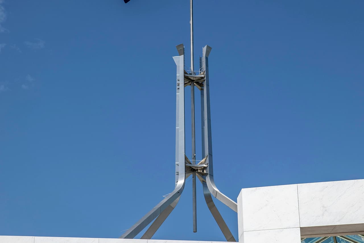 The Australian flag flying on the mast above Parliament House in Canberra