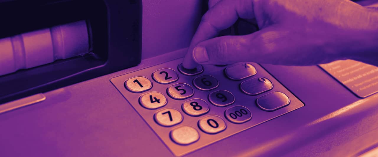 A finger pressing the keypad of a cash machine