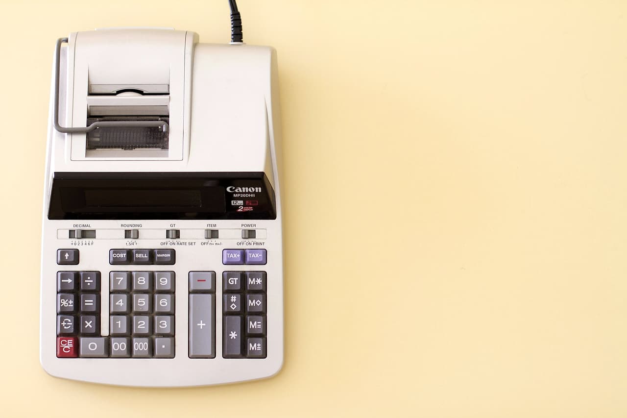 A grey printing calculator on a light yellow background