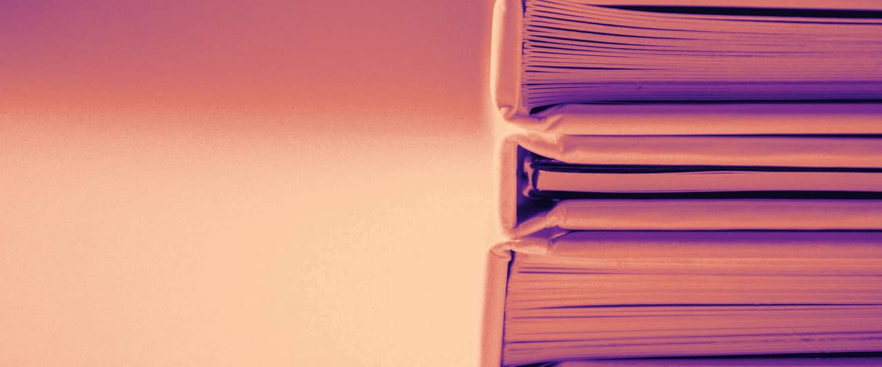 A stack of thick ring folders lying on a white surface