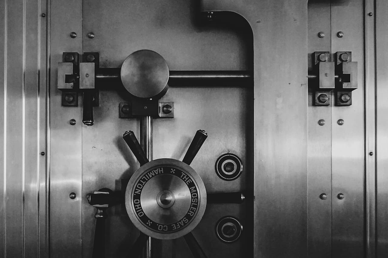 A steel vault door with a large locking wheel