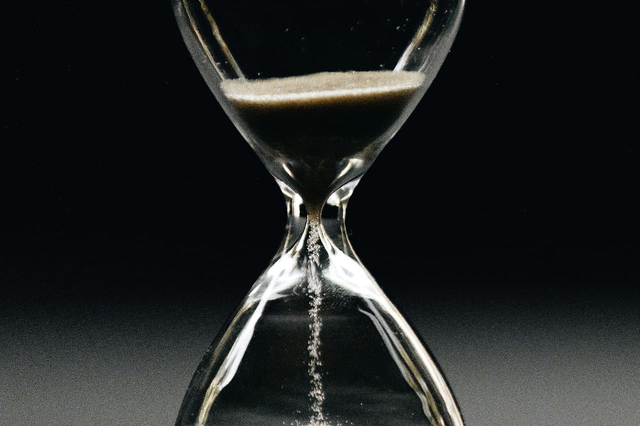 An hourglass with sand running through, on a dark background