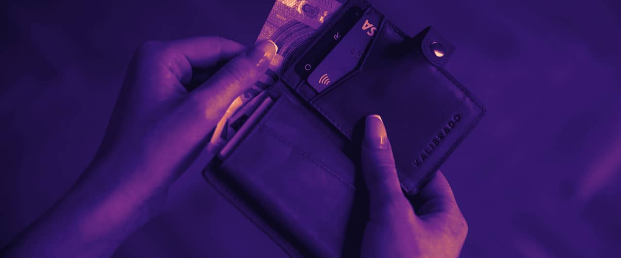 Two hands sliding a card out of a brown leather card wallet