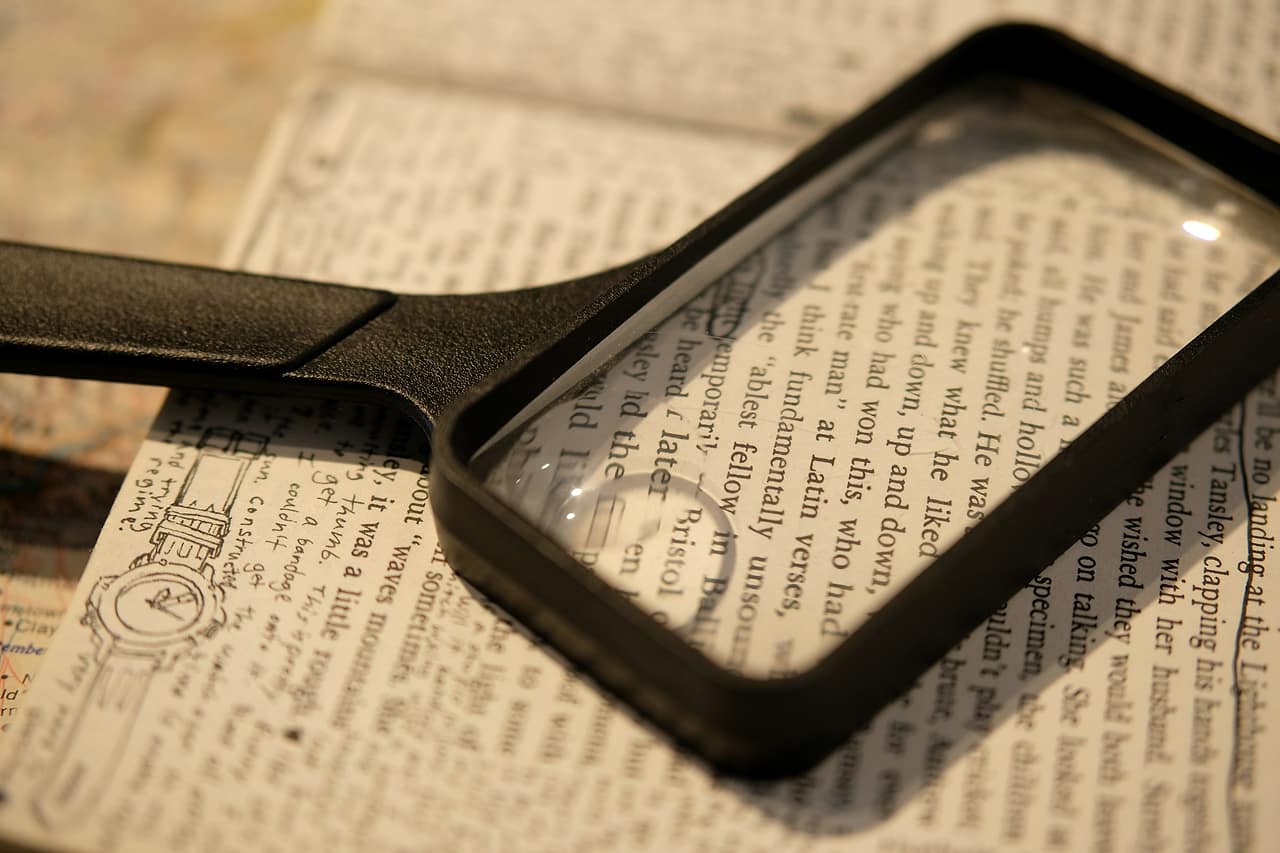 A black magnifying glass resting on a page of printed text