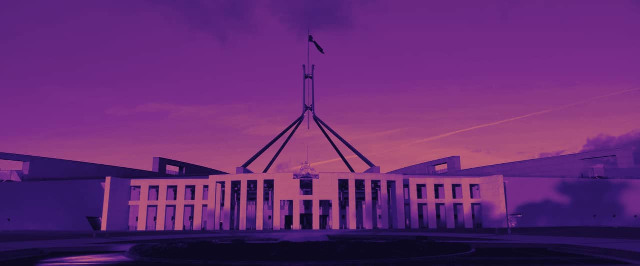 Parliament House in Canberra at sunset with its flag mast reflected in the forecourt pool