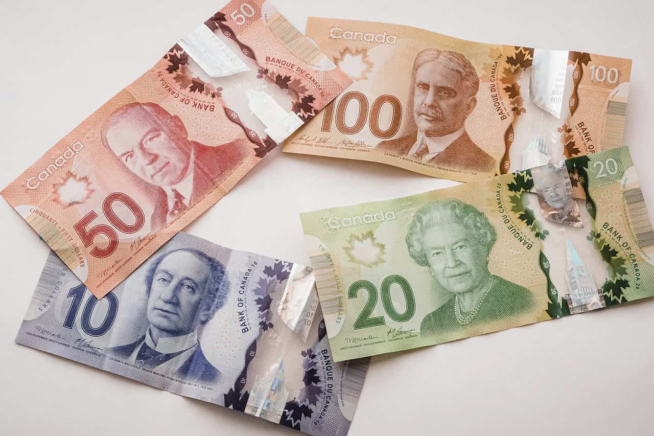 Canadian banknotes of several values fanned out on a white table