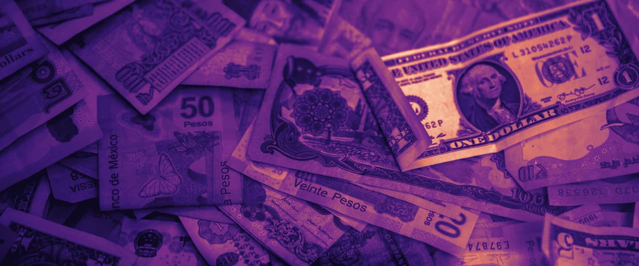 Banknotes from many different countries scattered across a table