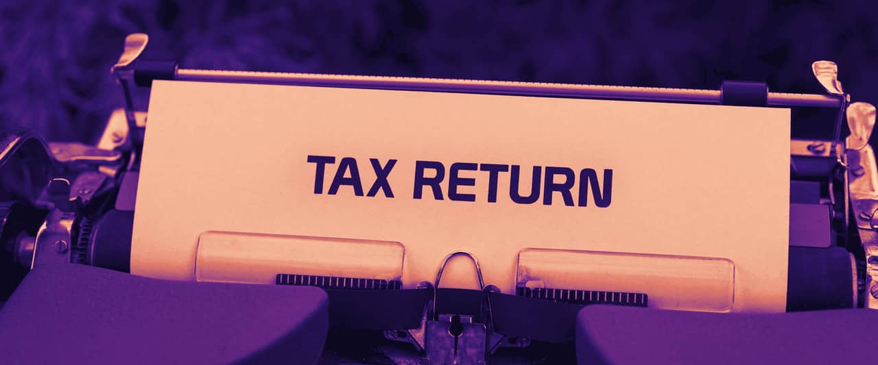 A sheet reading Tax Return in an old typewriter against green foliage