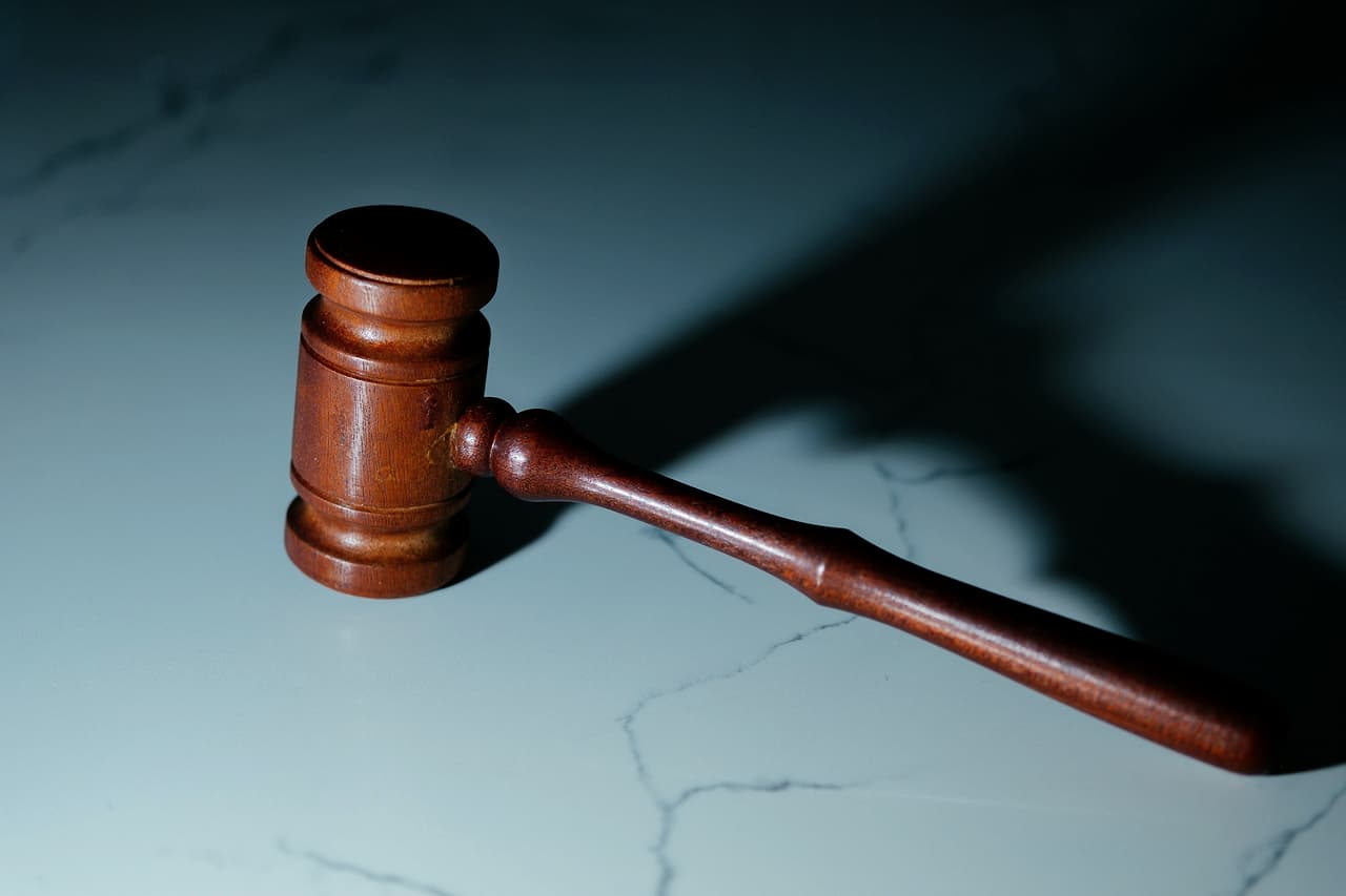 A wooden judge's gavel resting on a pale table