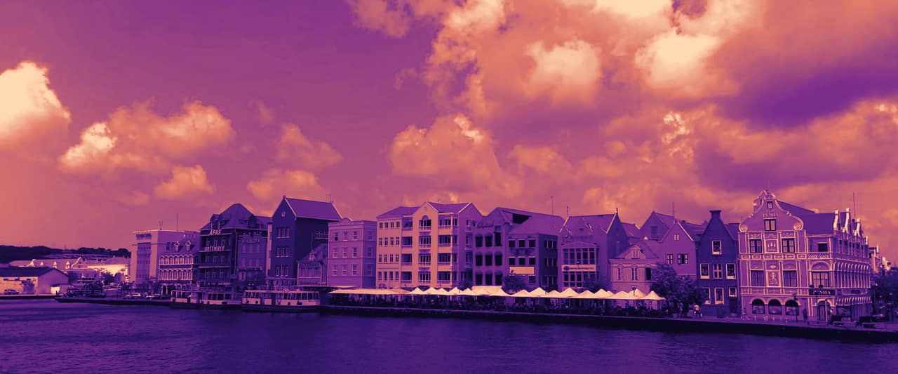 Brightly painted waterfront houses along a harbour under a blue sky with white clouds