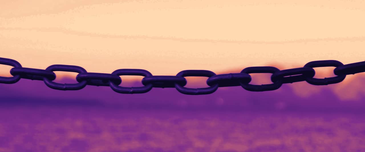 A metal chain stretched across the frame against a pale sea and sky