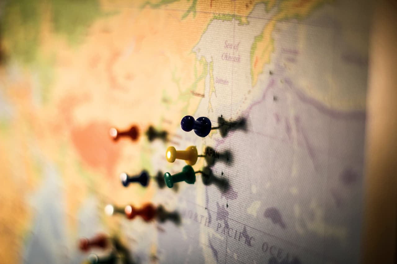 Coloured push pins stuck into a paper map, shallow focus