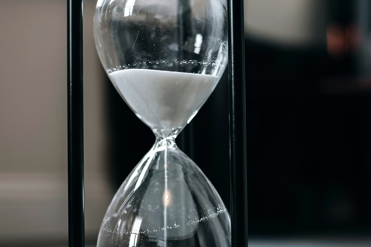 An hourglass with white sand on a wooden table