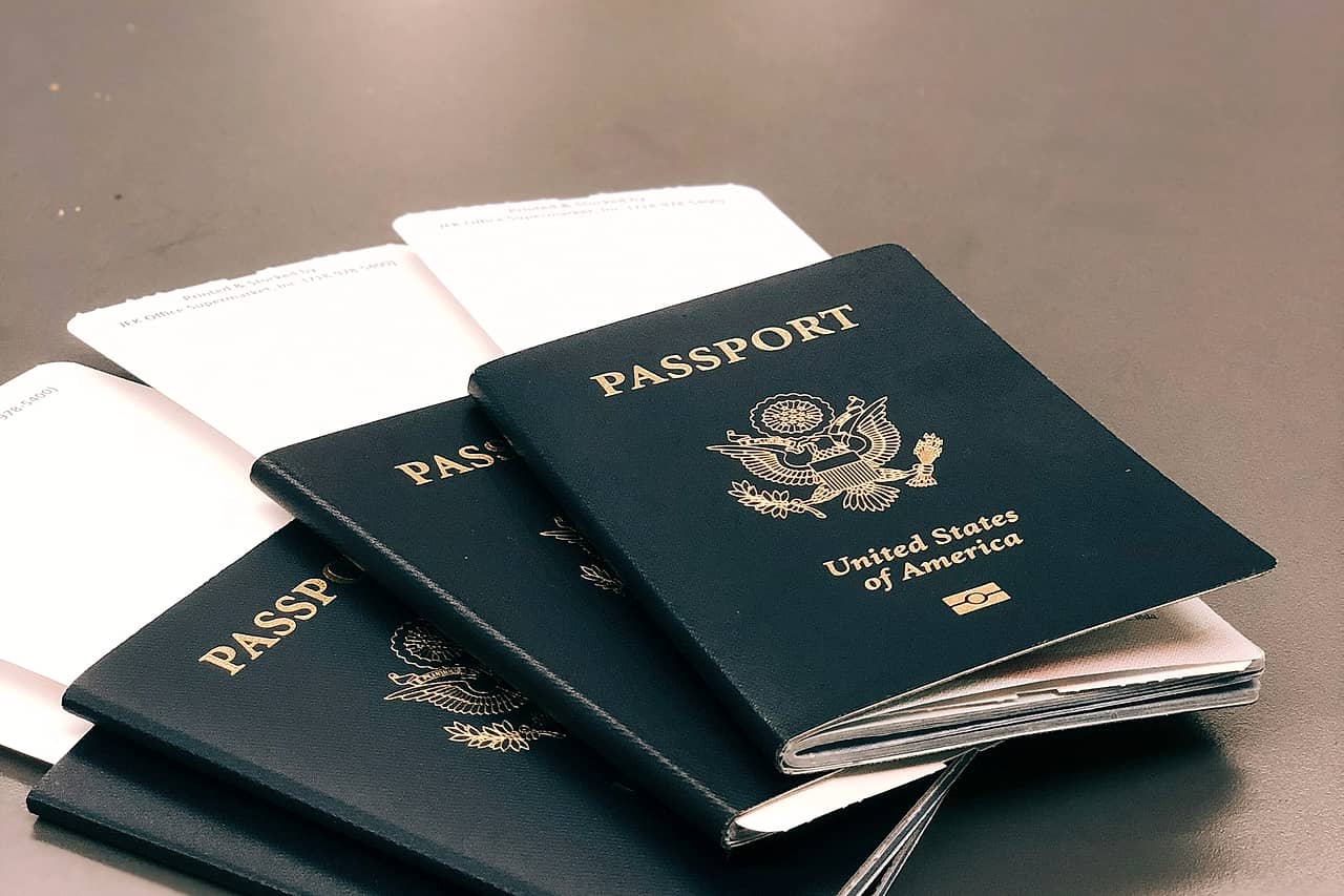 Four green passports fanned out on a grey table