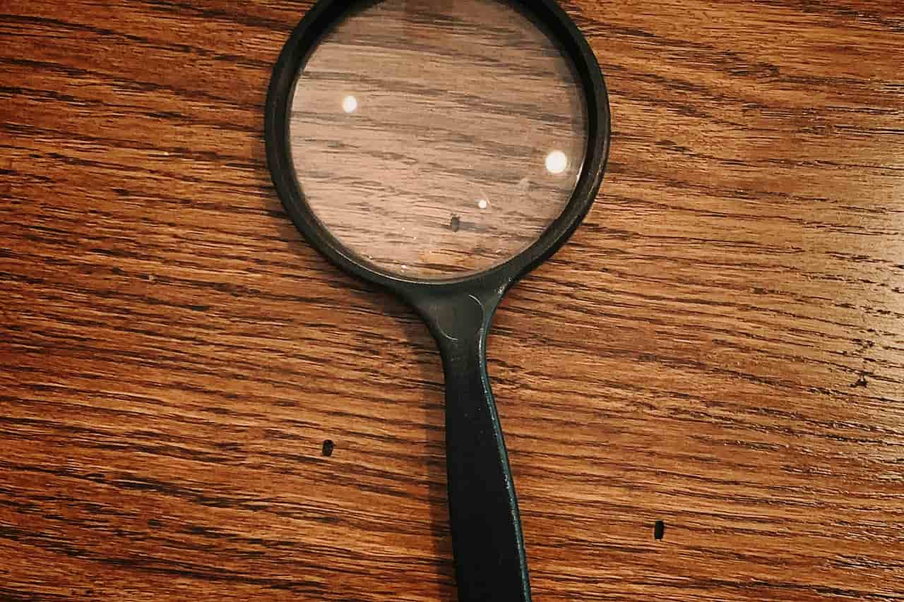 A black framed magnifying glass on a wooden surface