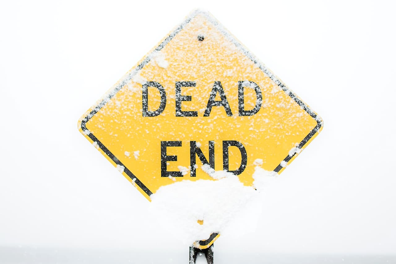 A yellow Dead End road sign crusted with snow