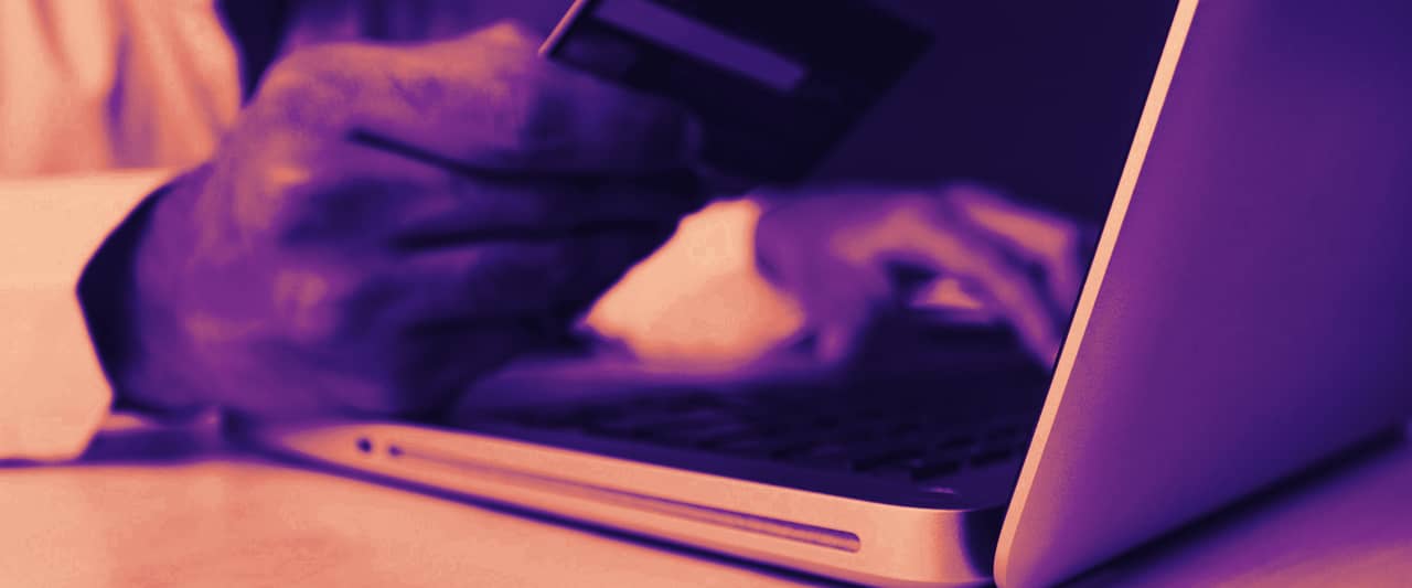 Hands holding a payment card over an open laptop keyboard