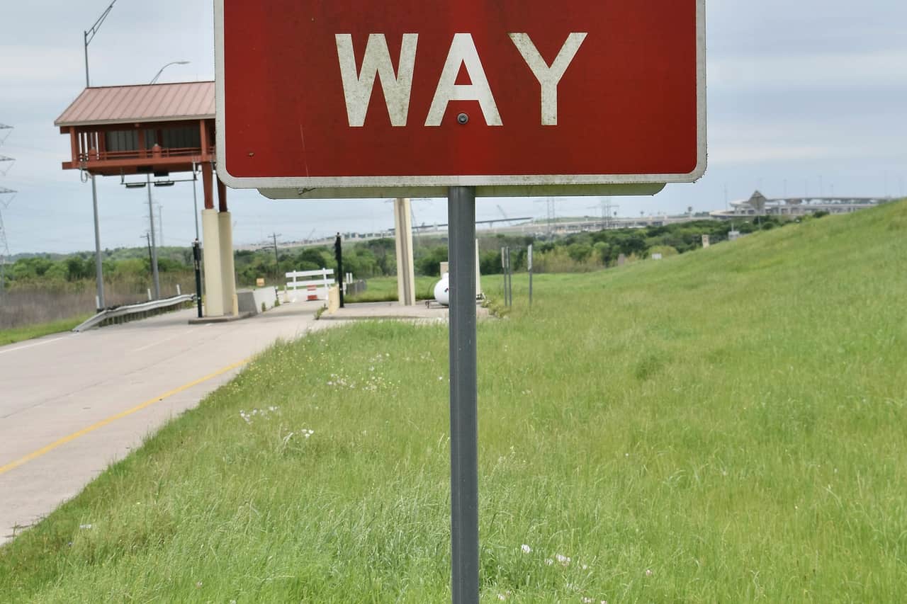 A red Wrong Way road sign beside a rural highway