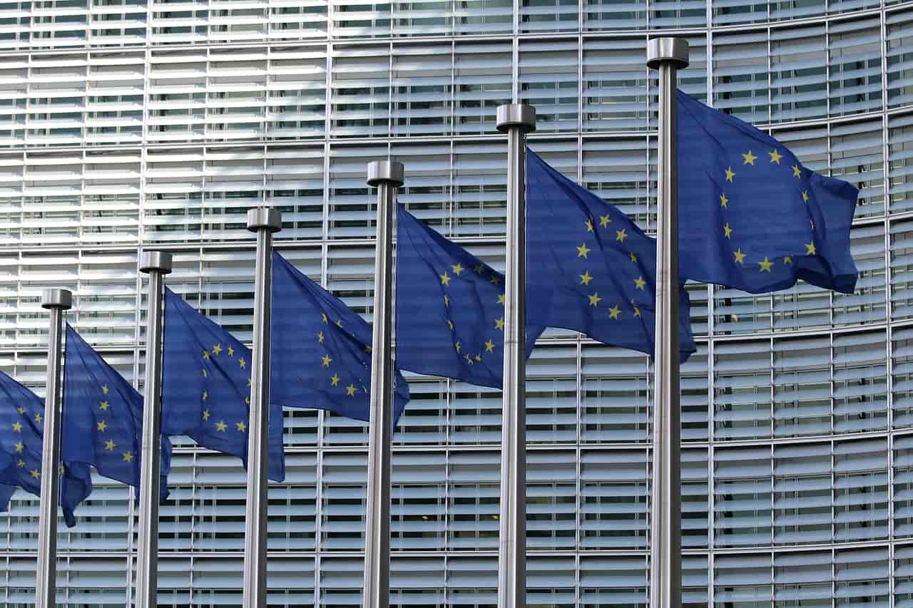 A row of European Union flags outside a glass office building