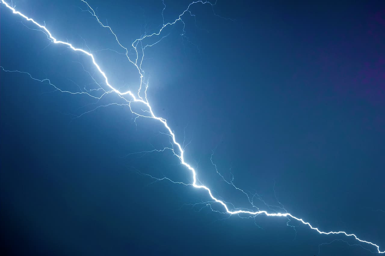 A single bolt of lightning crossing a deep blue sky