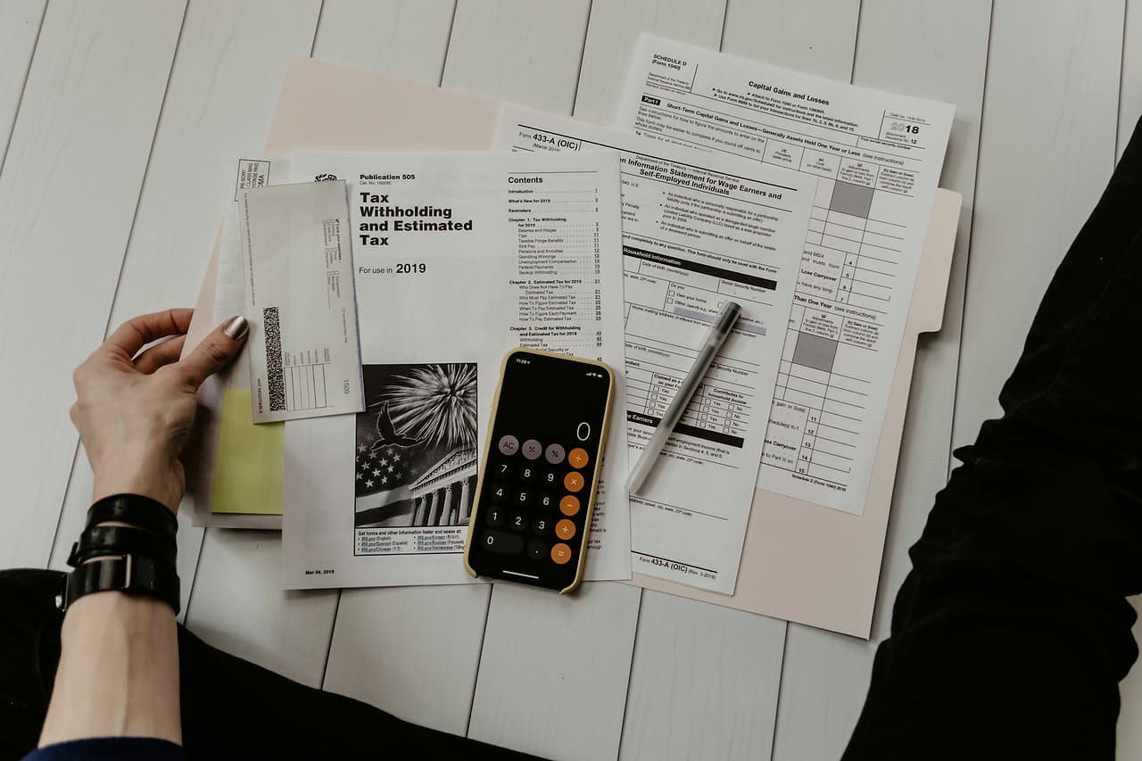 A person sorting receipts and papers beside a calculator
