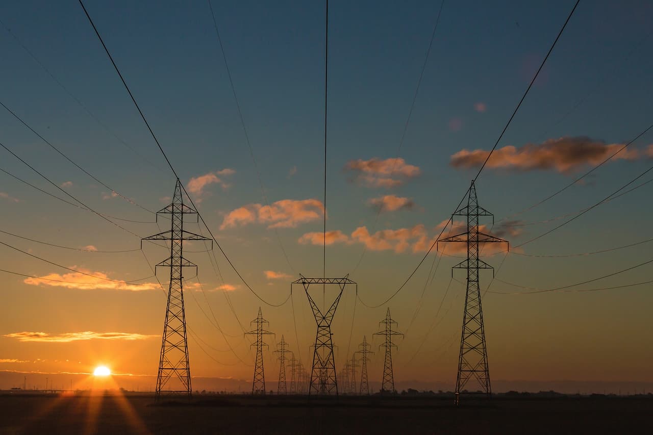 Electricity pylons and power lines against a sunset sky