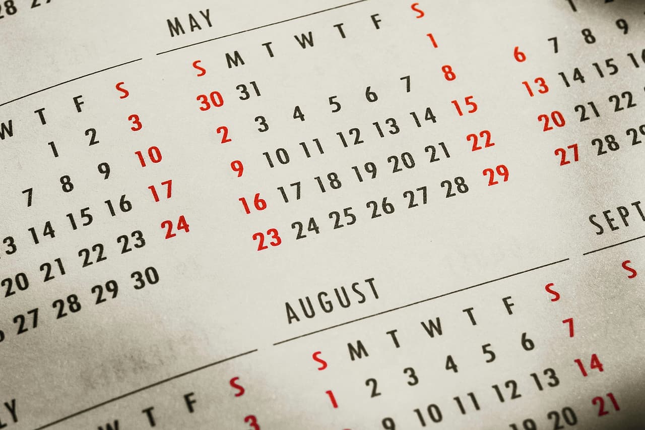 Printed monthly calendar pages with red and black dates