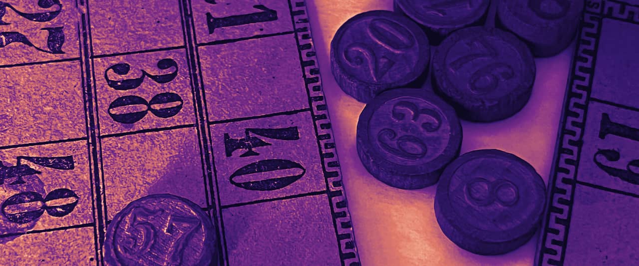 Old paper lotto cards and round numbered wooden tokens on a table