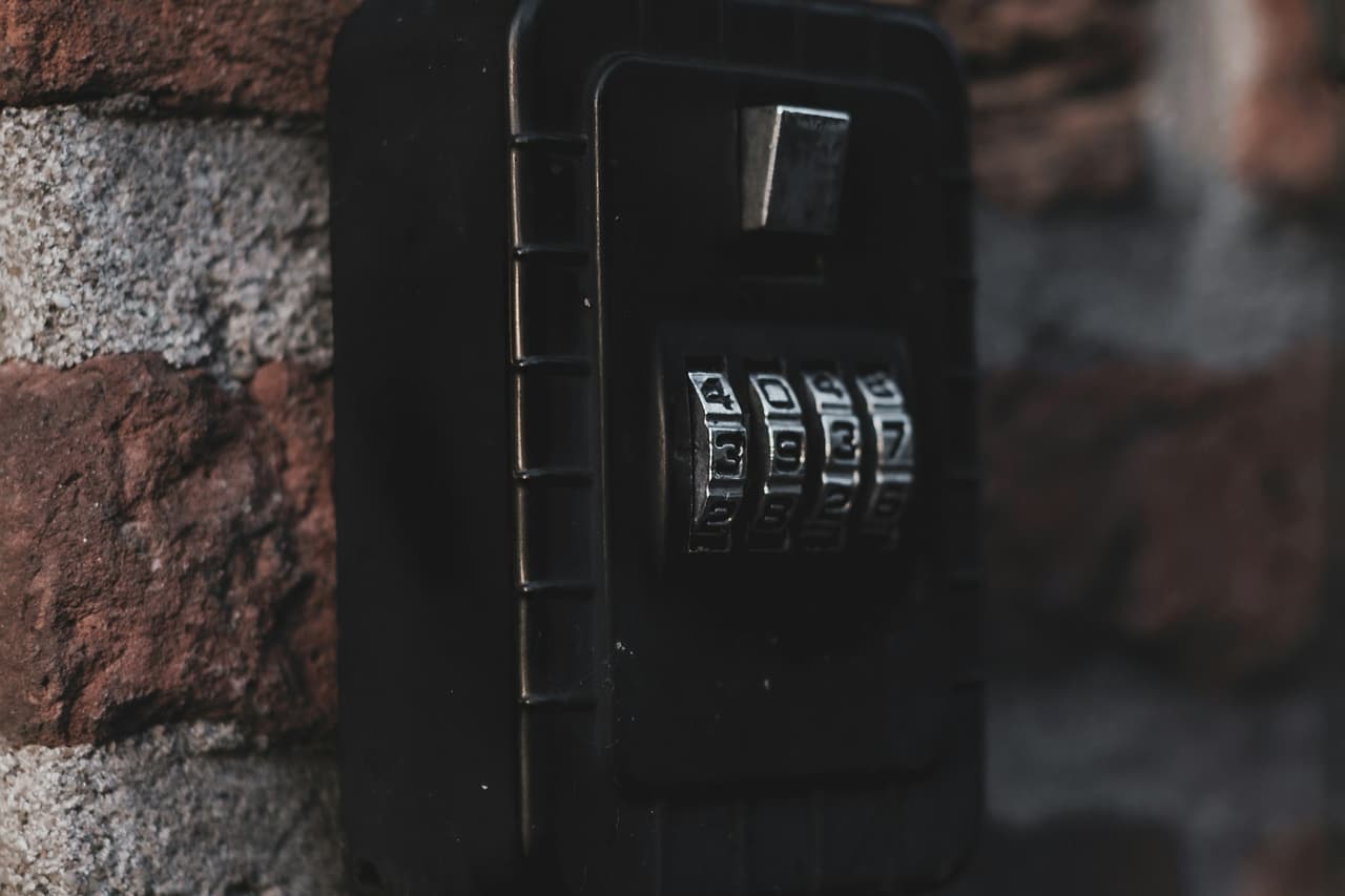 A black combination lockbox mounted on a brick wall