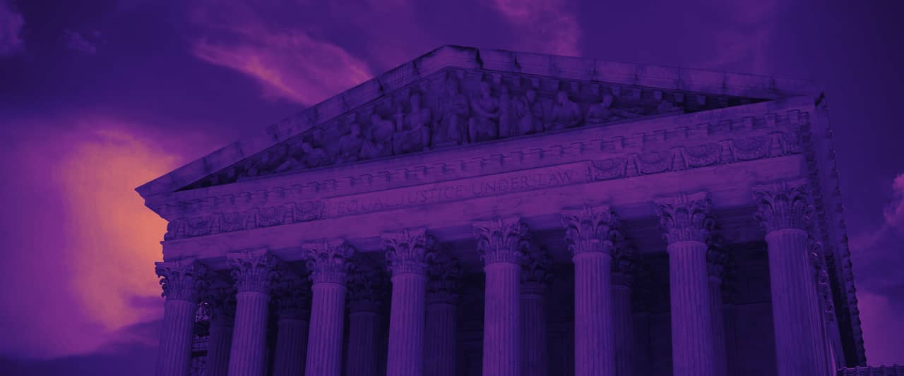 Columns and pediment of a neoclassical court building under a cloudy sky