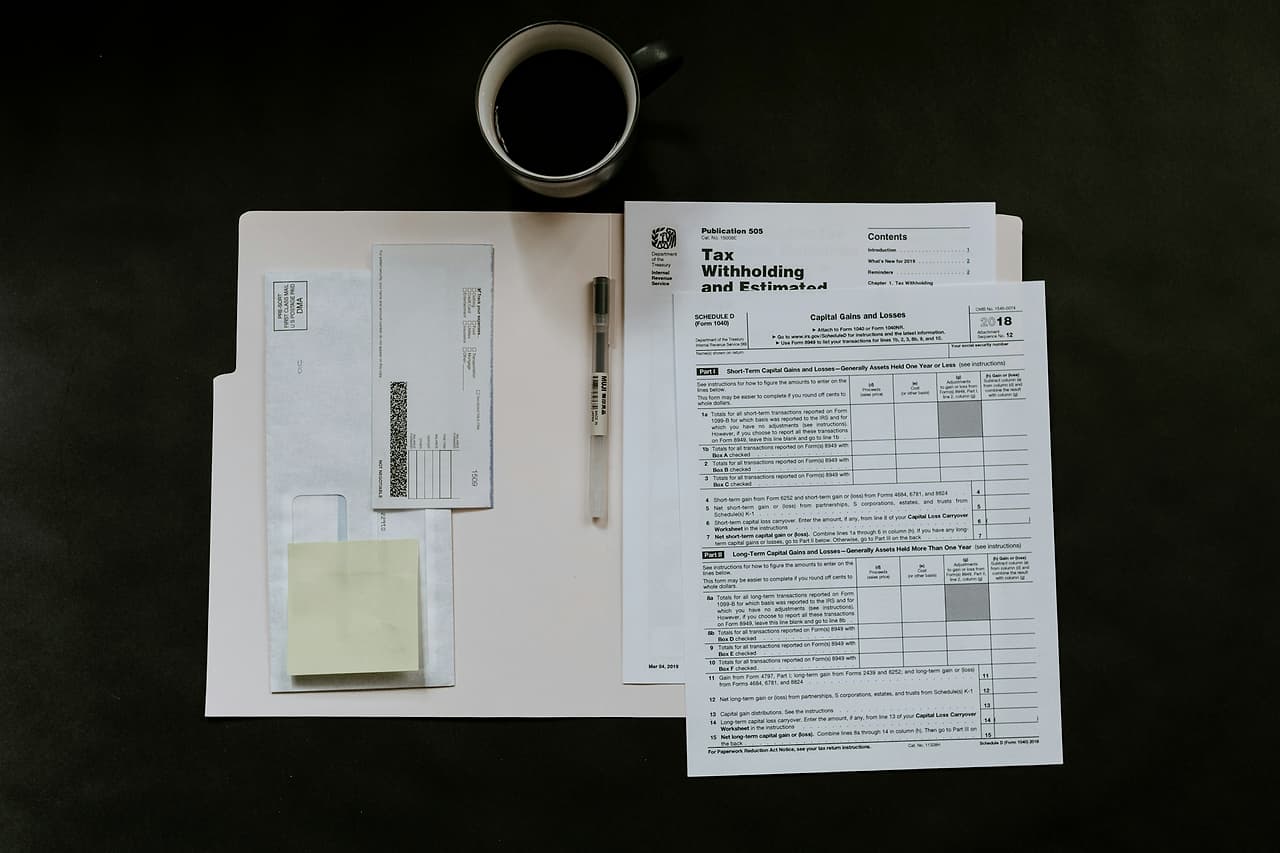 Printed forms and notes laid out beside a cup on a dark table