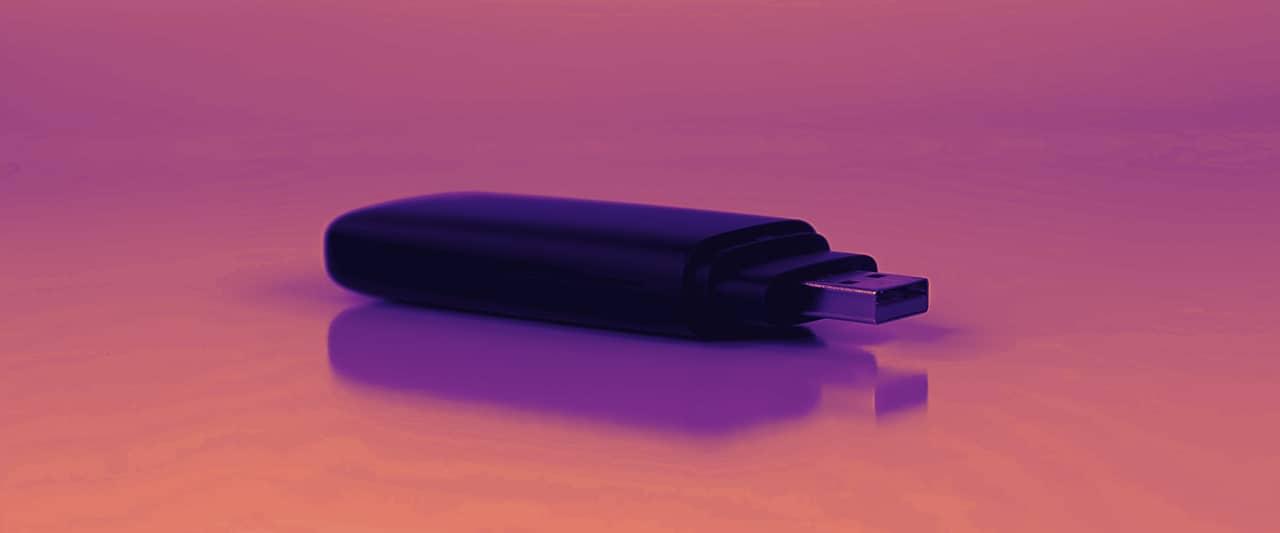 A small black USB device lying on a white surface