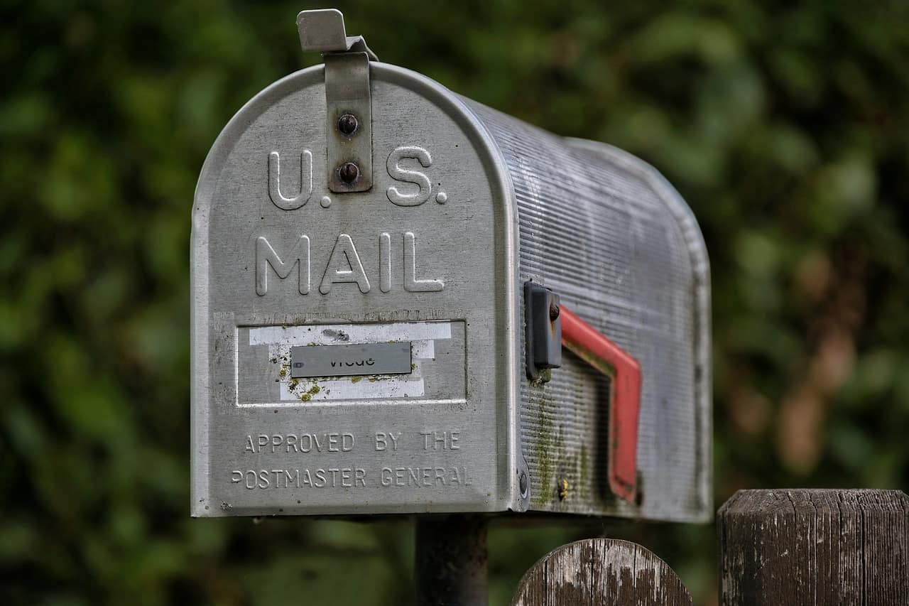 A weathered US mailbox with its red flag raised