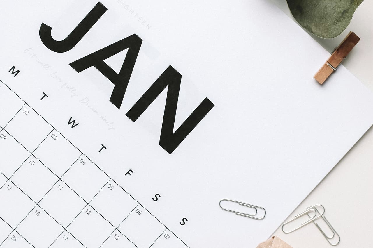 A January calendar page beside paper clips