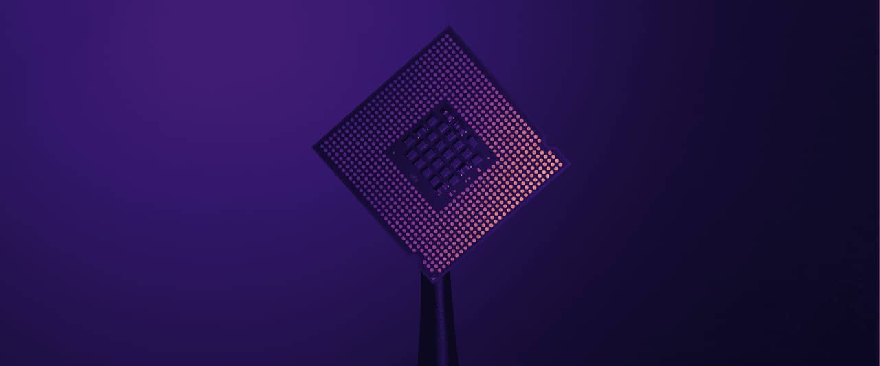 A computer processor chip held up by black tweezers