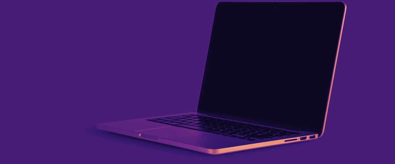 An open laptop with a dark screen on a plain grey table