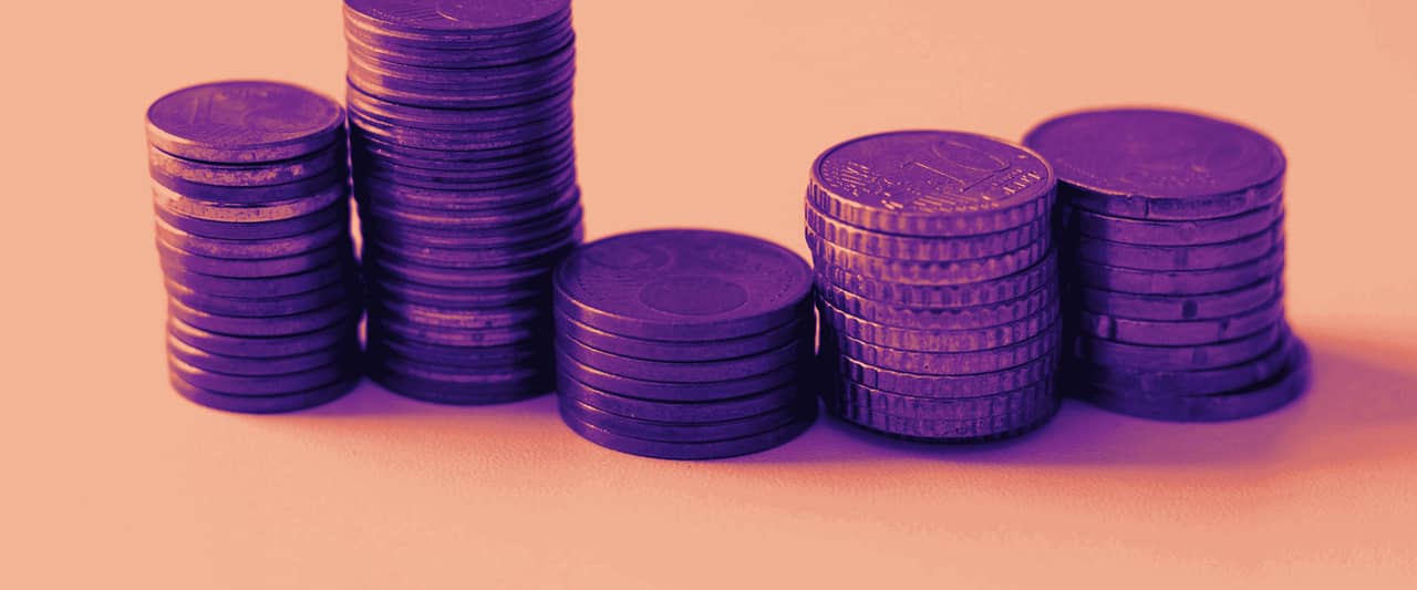Stacks of copper and gold coloured coins rising in height on a white surface