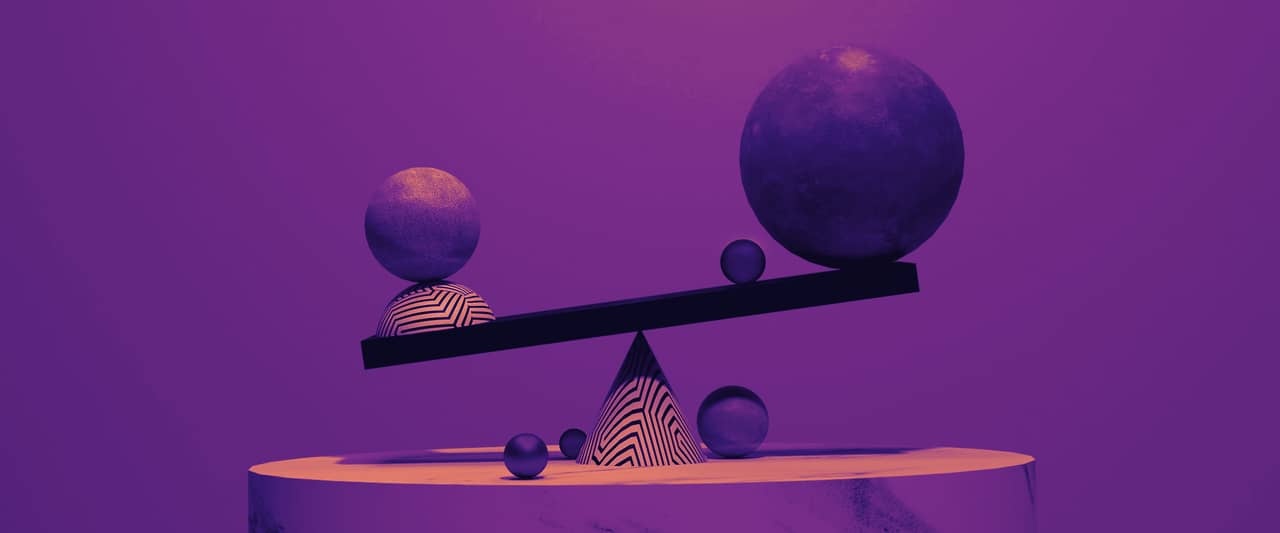 A sculpted balance with two spheres of different sizes on a marble plinth