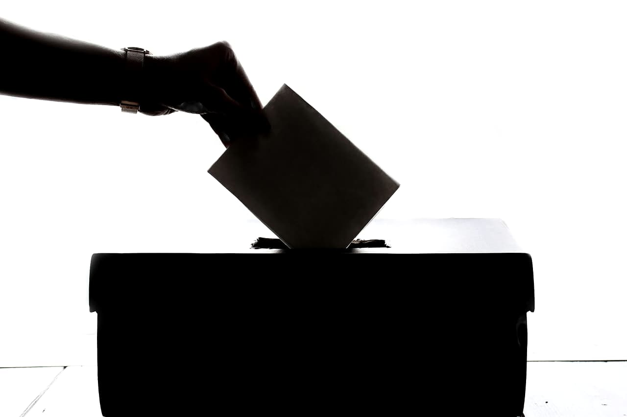 A hand dropping a ballot paper into a ballot box