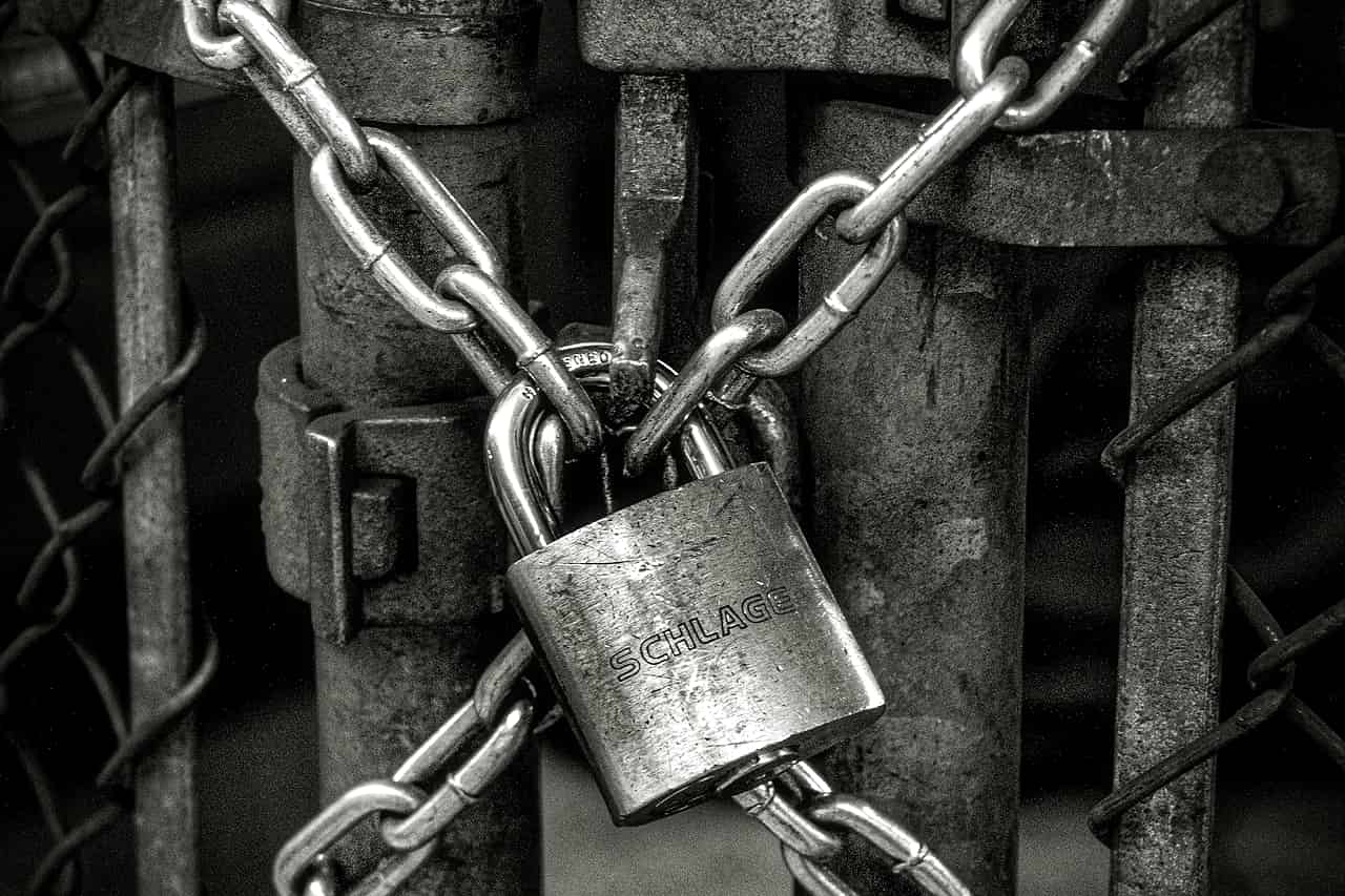 A steel chain and padlock wrapped around a weathered gate