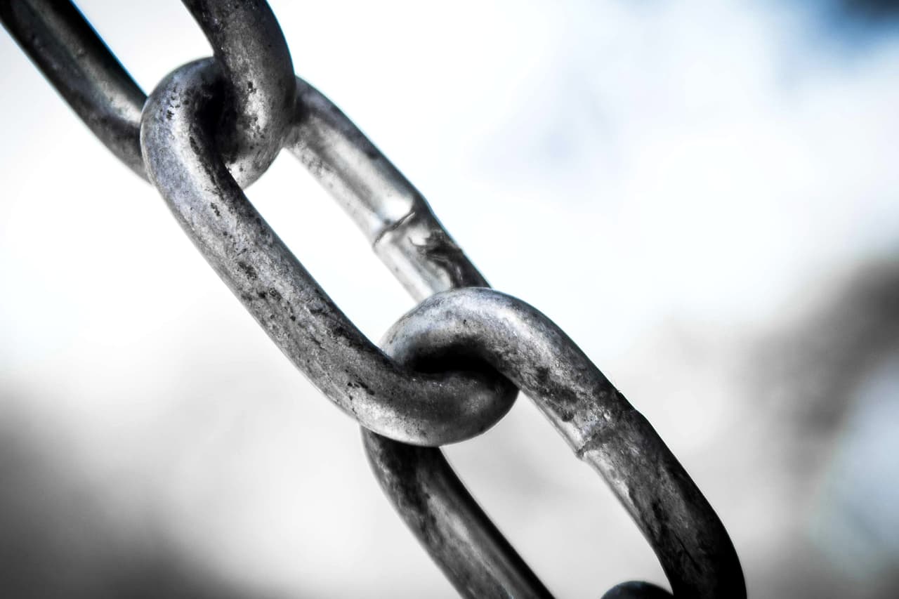 Close-up of a grey metal chain against a blurred light background