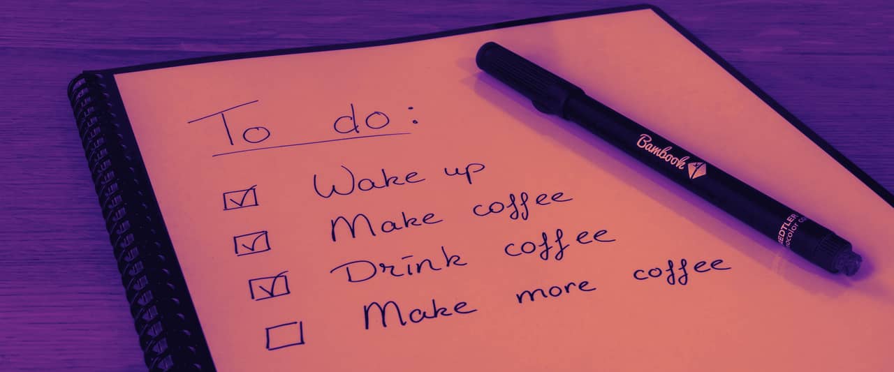 A notepad with a handwritten to do list and ticked boxes beside a pen