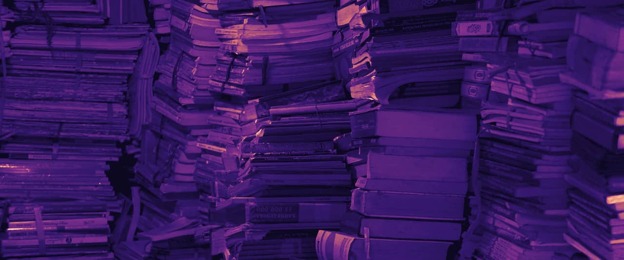 Stacks of old files and books piled high in a storeroom
