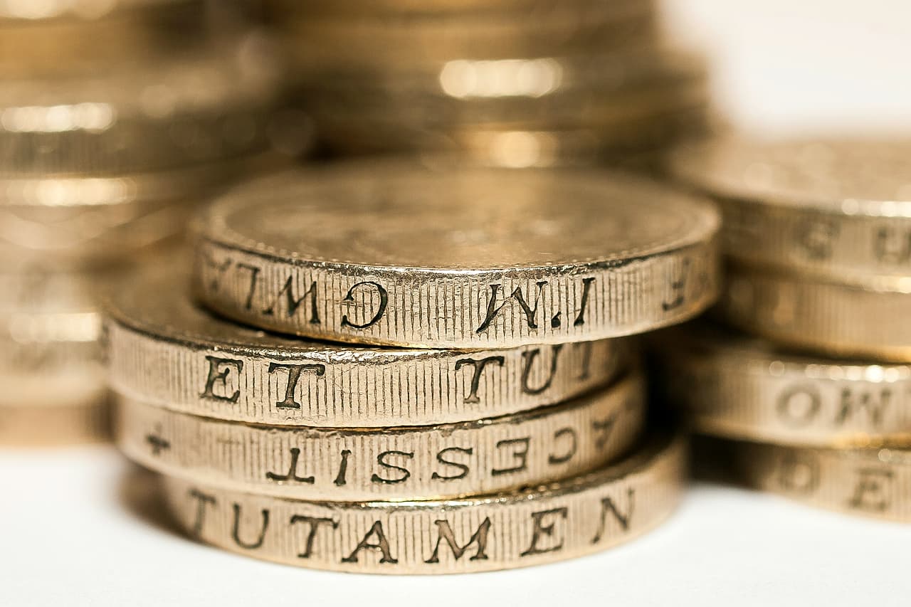 A pile of gold coloured pound coins on a white background